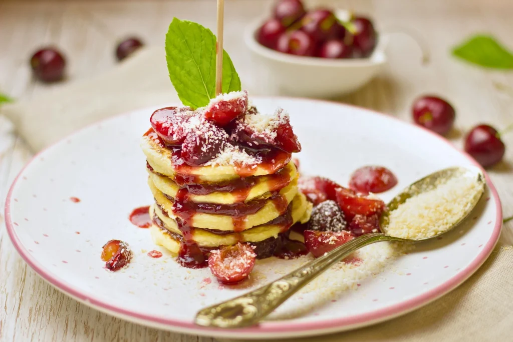 mini pancakes topped with fresh raspberries, blueberries, almond slices and honey.