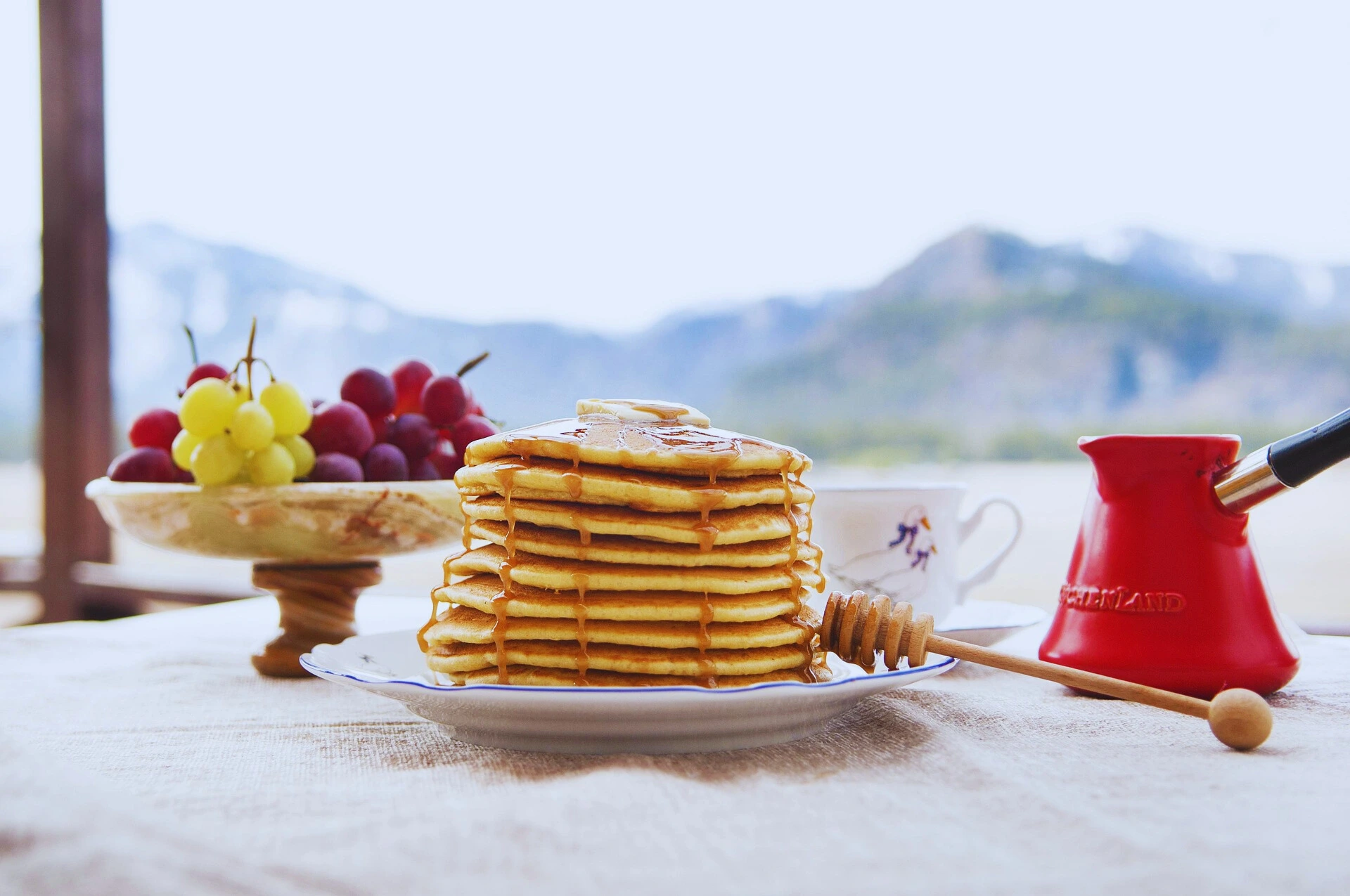 Outdoor breakfast with sourdough pancakes, honey, and fresh fruit.